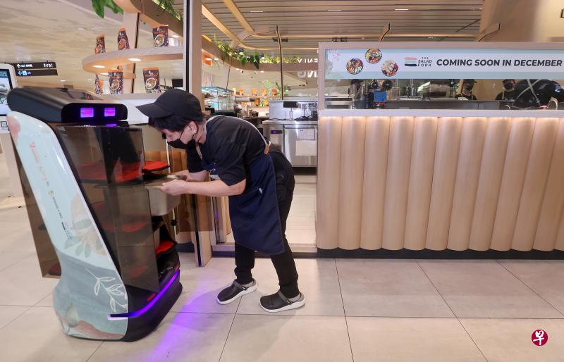 餐饮店“旺”加入到数码化革新中，引进可以运送物品的智能机器人，减少部分人力，也减轻年长服务员的日常工作强度。（萧紫薇摄）
