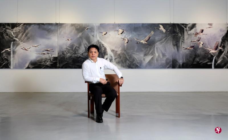 画家范少华和展览最巨幅代表作、长达8米的仙鹤油画合影。