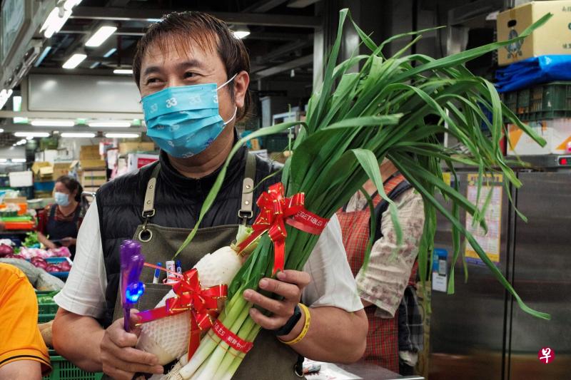 在台湾的选举文化中，葱、蒜、萝卜等蔬菜因为谐音意味“充（葱）满胜算（蒜）”“好彩头”（萝卜闽南语称作菜头）被视为幸运物。图为一名男子从以无党籍身份参选台北市长的黄珊珊手中，接过“幸运蔬菜”。 （法新社）