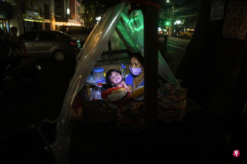 阿巴瓦格母子住在马尼拉市郊一座共管公寓外的手推车内，雨天就会拉起一块透明塑料布，以免被淋湿。（法新社）