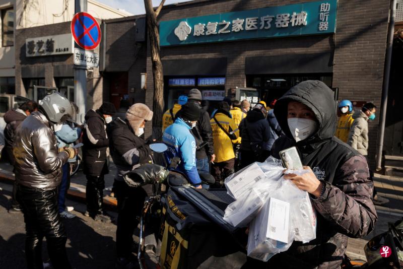 在宣布放宽无症状、轻症冠病感染者居家隔离后，中国国家卫健委专家梁万年指出，接下来要严防出现医疗资源挤兑等问题。图为7日北京一处药局外，大批外送员等待领取代为采购的抗原检测试剂盒和药品。 （路透社）
