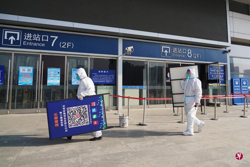 中国官方本月初宣布不再查验跨地区流动人员健康码后，青海省西宁市火车站的两名工作人员把要求扫码的告示牌移除。（法新社）