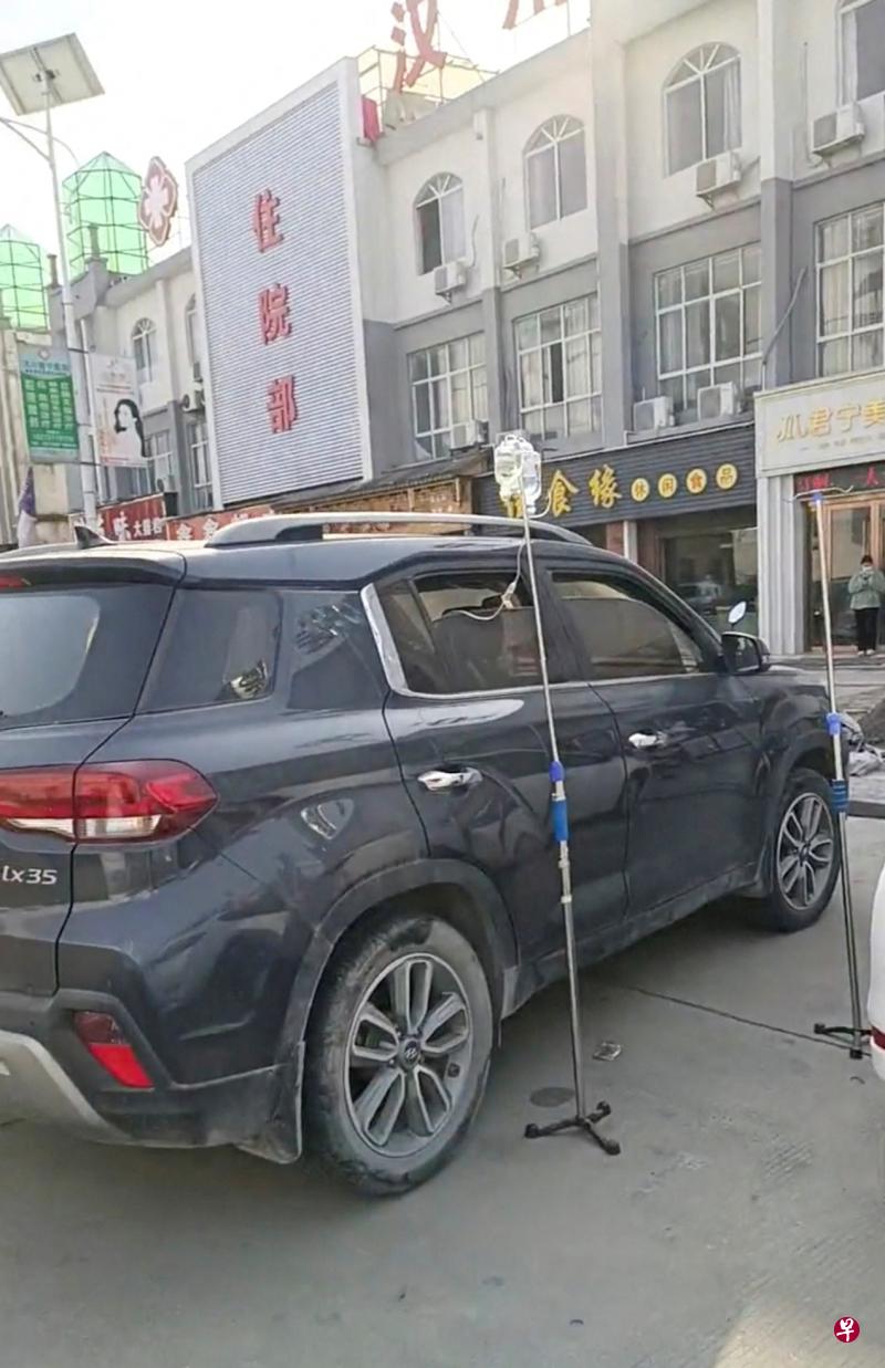 冠病疫情在中国大范围蔓延，多地医疗资源短缺，一些医院人满为患。图为湖北汉川市，病患在医院外坐在车里打点滴。（路透社）
