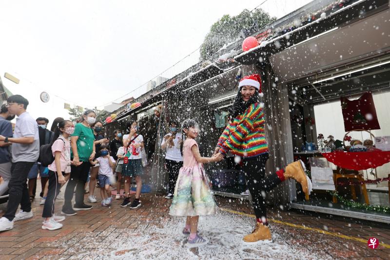 牛车水圣诞市集现场，参与者们穿上圣诞服饰，在飘落的雪花中，牵起手跳起舞，感受别样的冬日气息。（邝启聪摄）