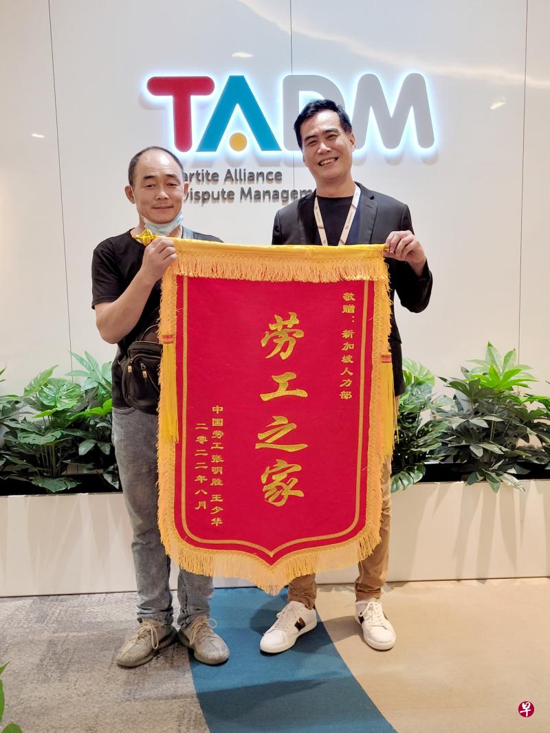 客工张明胜（左）为感谢劳资政纠纷调解联盟调解员梁挺焕，特地订制锦旗表达谢意。（受访者提供）
