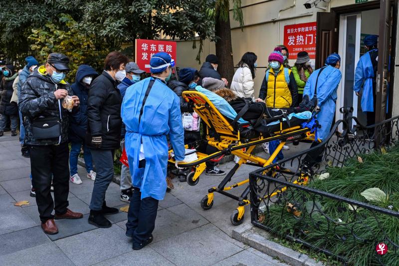 随着中国大陆冠病感染人数激增，大量医护人员也被感染，中国多地医院人手不足，医疗系统遭遇严峻挑战。图为星期一（19日）上海复旦大学附属华东医院外，医护人员将一名病人送往发热门诊就医。（法新社）
