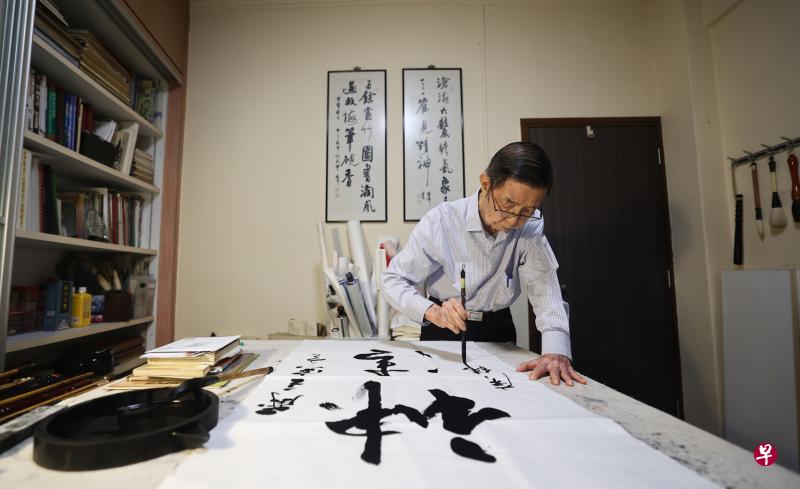 书法家曾广纬在书房大长桌上写字。书架上是各类书法参考书与历代书家法帖。（陈渊庄／摄）
