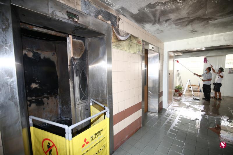 电动踏板车在电梯内爆炸，导致20岁的送餐员伊凡严重烧伤丧命。图为事发隔天的情景，电梯内外被烧得乌黑，清洁工在电梯外清洗。（档案照片）