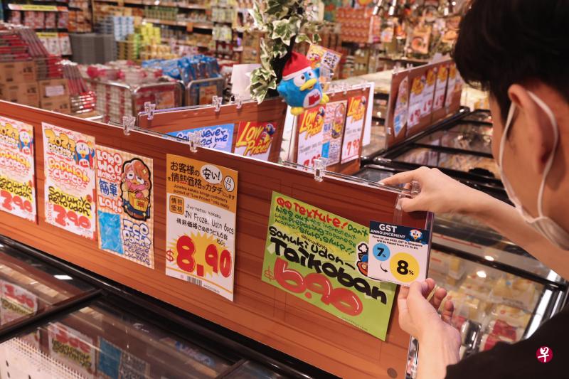 日本连锁超市Don Don Donki义顺纳福城分店的工作人员在货架上张贴告示牌，说明消费税调整为8%。（邬福梁摄）