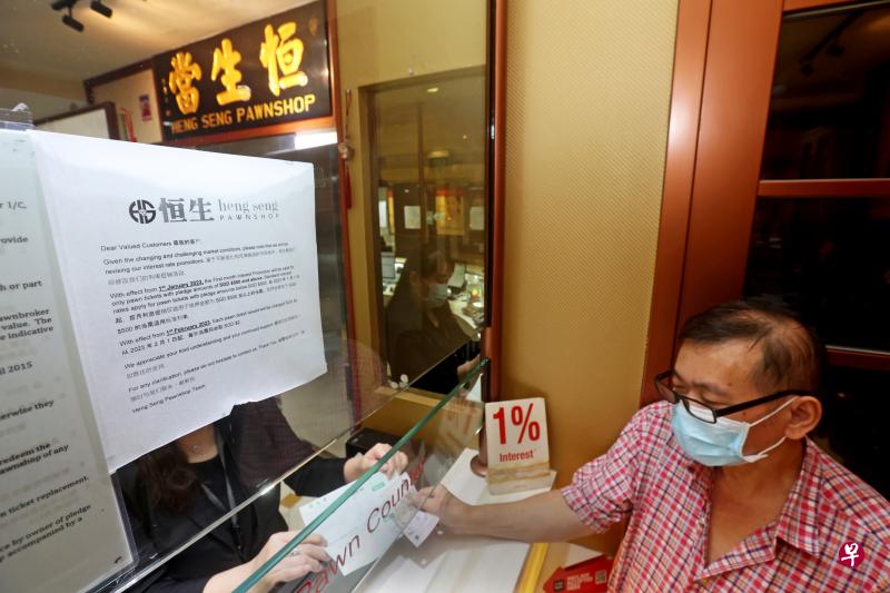 大巴窑恒生当估价师许美玲（黑衣者）把当票交给当客郑炎星，并收取2元费用。（关俊威摄）