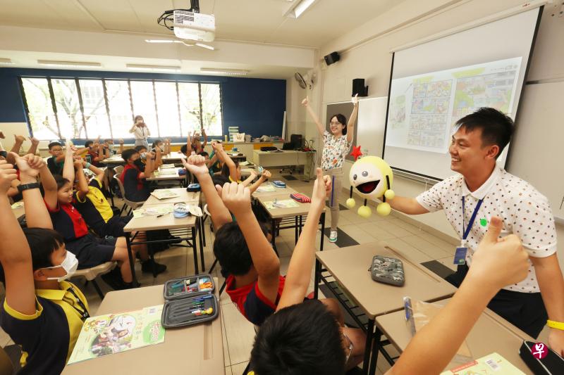 《大拇指》美术员翁俐雯（中、高举双手者）向安德逊小学小五一班学生介绍新漫画《拇指兵团》，学生反应热烈，跟“大拇指”玩偶互动。（邝启聪摄）