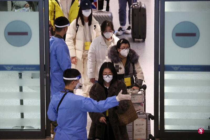 图为1月4日在仁川国际机场，身穿蓝色防护服的韩国士兵指示一群挂着黄色牌子的中国游客前往指定的冠病检测点。（路透社）