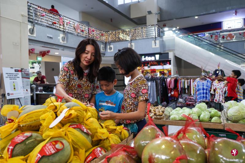 谭媜娜（左）每周都会到住家附近的邻里商店购买食品和生活用品，最近赢得邻里节幸运抽奖，让她很开心。图为谭媜娜带两个孩子洪国恩（中）和洪乙玄（右）在伊莱雅购物中心买菜。（白艳琳摄）