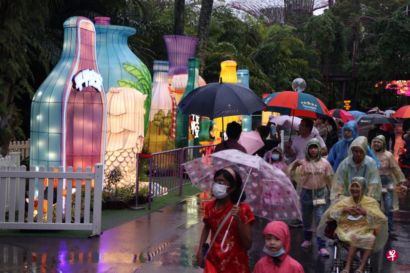 公众撑着伞穿着雨衣，风雨不改到春到河畔感受新年气氛。夜幕低垂，灯饰亮起，细雨纷飞，为春到河畔添了一层朦胧美。（梁麒麟摄）