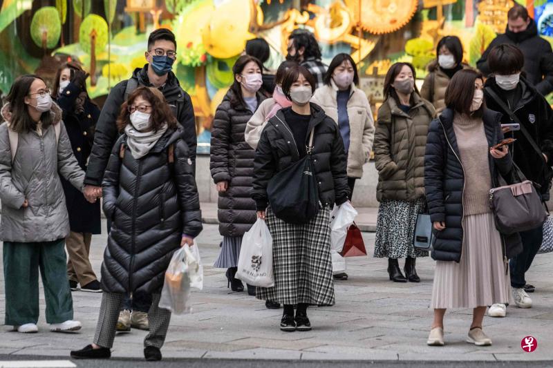 日本多家媒体发布的民调结果显示，多数受访日本民众认为就算政府解除规定，他们外出时还是会继续戴口罩。图为1月27日的东京街头，几乎每个人都戴着口罩。（法新社）
