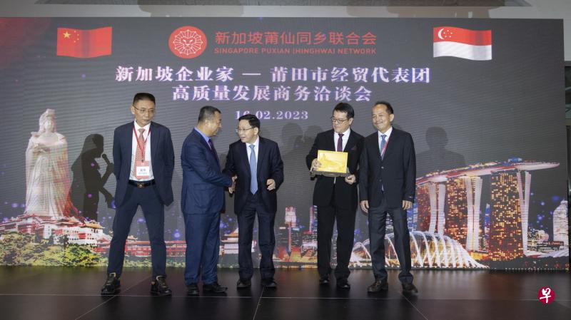 在商务洽谈会上，莆仙同乡联合会会长方志忠（左二）与莆田市委书记付朝阳（中）互赠纪念品。与会者包括莆仙同乡联合会执行会长吴伟（左一），以及莆仙同乡联合会两名副会长周家萌（右二）和张志建。（陈来福摄）