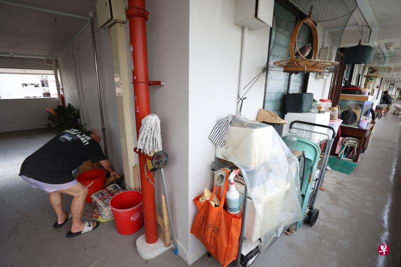 记者到场访问时，恰好碰到在走廊整理杂物的屋主洪赐福，他在走廊和电梯外的公共空间堆积了不少杂物。（梁麒麟摄）