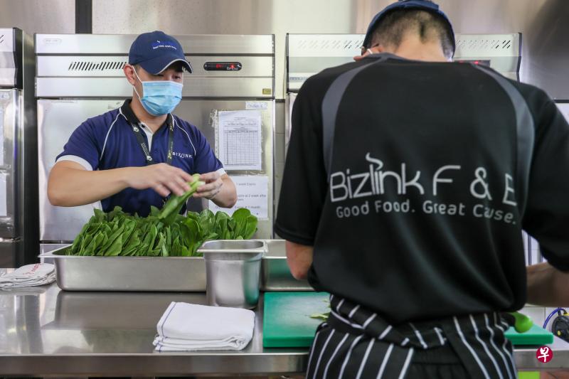 商联中心指导员张迎帆（左）在中心设于心理卫生院的专业厨房里，指导一名培训生切蔬菜。到这个厨房接受培训与入职训练的培训生，包括由心理卫生学院推荐的康复中病人，以及其他社服转介的体障者。（卓祾祎摄）
