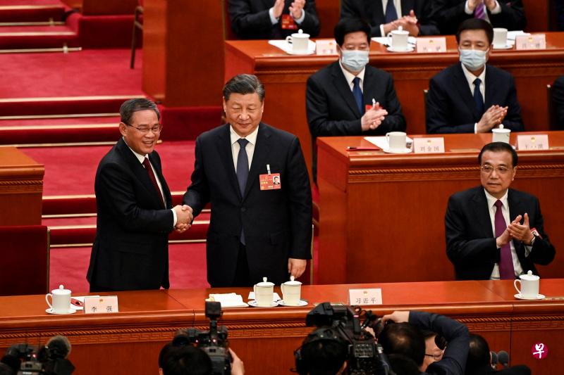 　中国国家主席习近平（中）在全国人大会议上与新任国务院总理李强（左）握手；卸任的国务院总理李克强（右）鼓掌祝贺。（法新社）