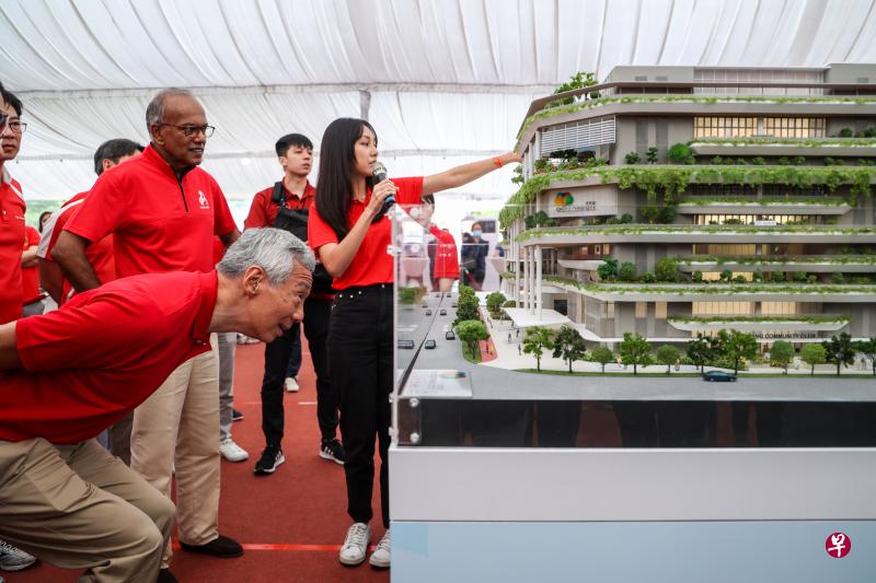 李显龙总理（前）在律政部兼内政部长、义顺集选区议员尚穆根（左二）陪同下，聆听有关忠邦城新设施的讲解。这个占地0.9公顷的综合发展项目，集民众俱乐部、巴刹、熟食中心、游泳池、健身房、社区花园和商店于一体。（白艳琳摄）