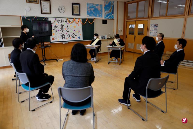 日本福岛县天荣村的汤本中学星期五（3月31日）送走最后两名毕业生（面对镜头者）后无奈关闭。学校教师在毕业典礼给毕业生戴上胸花，这通常是学弟妹的任务。（路透社）