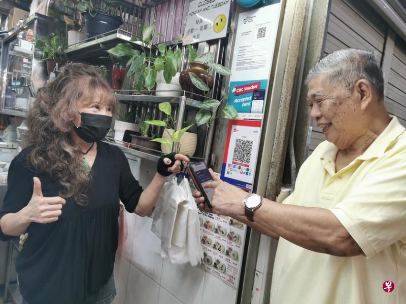 王书民（右）使用社区发展理事会邻里购物券，向在马林台巴刹与熟食中心经营粥摊位的林姓摊主买粥。（受访者提供）