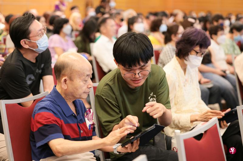 义安理工学院华文传媒系的学生热心地辅助乐龄学员，尝试刚学到的数码技能。（李冠卫摄）