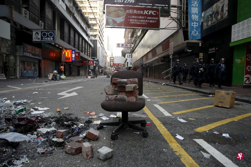 暴民凌晨从人行道上挖出地砖，作为攻击警察的武器，一些砖头还留在现场这张椅子上。（法新社）