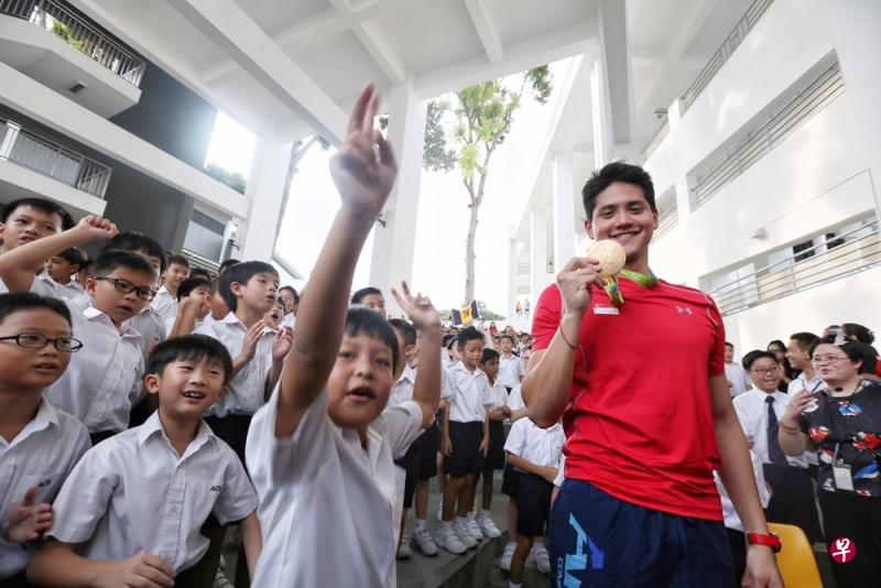 约瑟林步出礼堂后，握着金牌与小学生们合照。（陈佩敏摄）