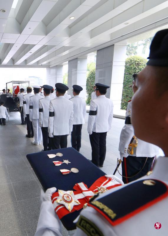 扶灵队将盖上国旗的灵柩放进拖曳炮架上的钢化玻璃保护外壳，准备开离国会大厦，前往举行国葬仪式的国大文化中心。（何家俊摄）