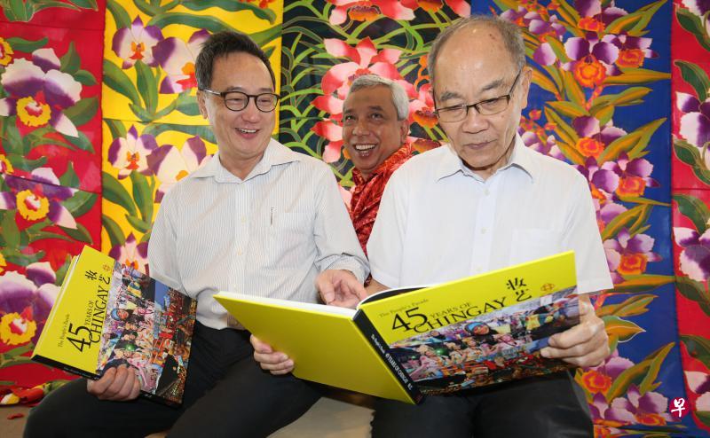 本地诗人、《新明》总编辑潘正镭（左起）、峇迪艺术家依卡和书法家林书香，共同参与今年妆艺大游行《又见花同心》的演出。潘正镭和林书香翻阅的是人协出版的《妆艺45：我们的节庆游行》纪念册。（周柏荣摄）