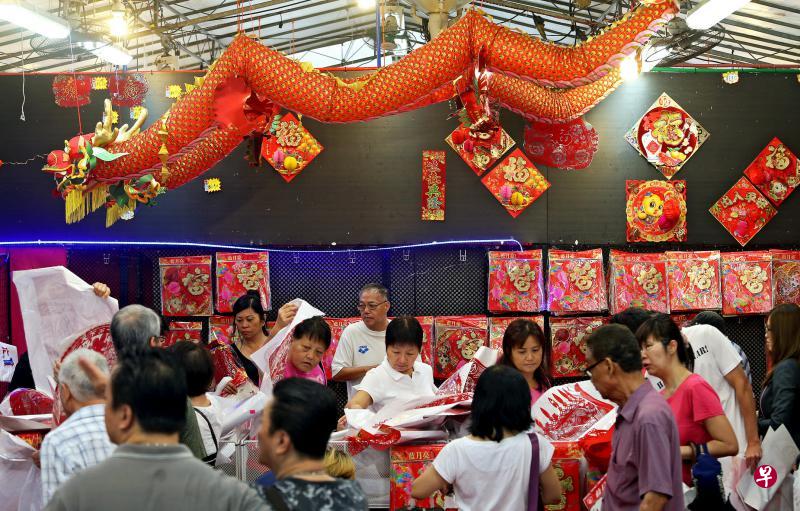 宏茂桥组屋区的百货商店昨天免费赠送新年装饰品，许多公众兴致勃勃地挑选对联、福贴和剪纸。（叶振忠摄）