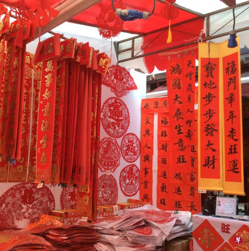 以往巴刹和街边有挥春的档口，铺满垂挂的各类春联，今天春联在大商场里高挂着，供人们选购。今昔过节形式或有不同，不变的是人们过节的喜庆心情。（档案照）
