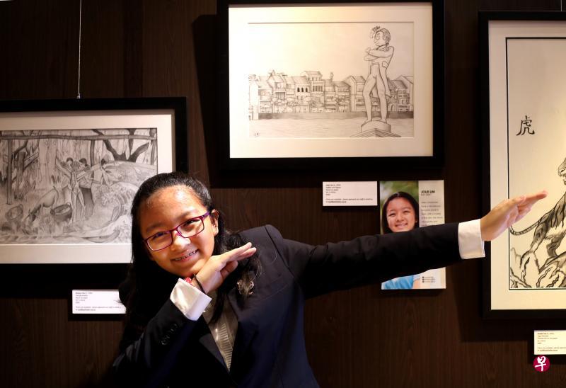 　林卓萦摆出可爱的姿势和作品“莱佛士和鸽子”合照。（龙国雄摄）
