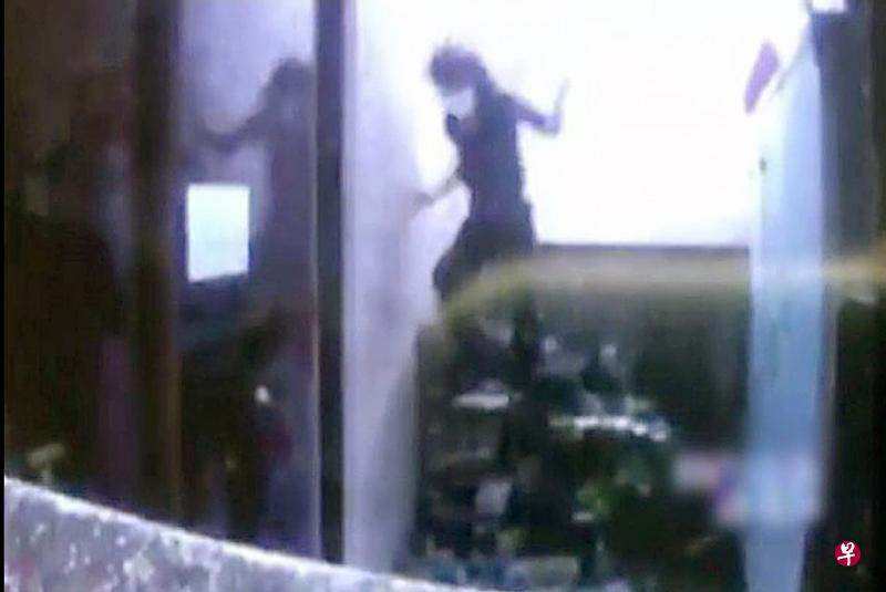 民防人员利用水柱将狮城女冲到地板上。（联合新闻网）