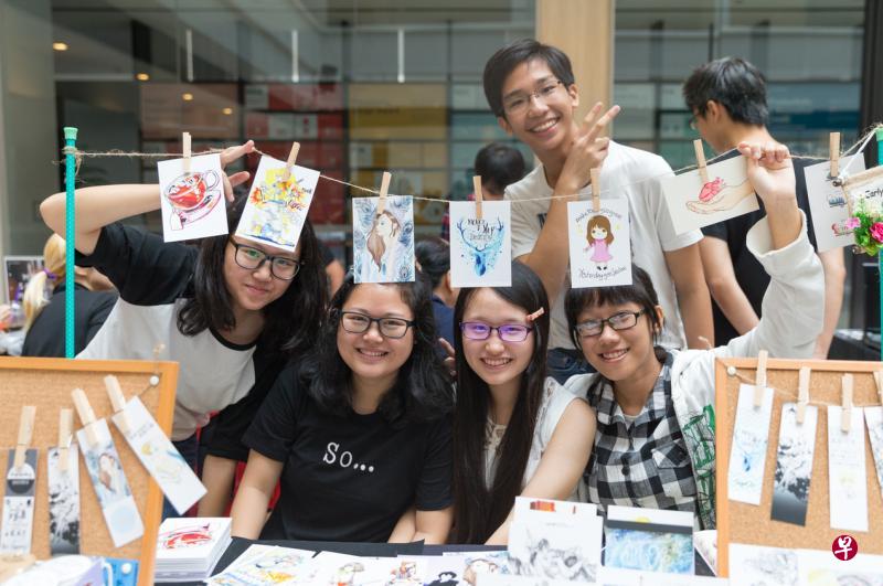美术通讯员参与“新加坡原创漫画节”举办的创意市集，摆摊售卖印上自己画作的书签、明信片和徽章等产品。（档案照）
