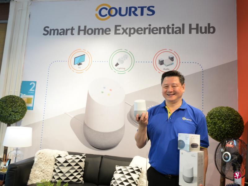 COURTS新加坡总裁陈发明握着Google Home，展示小巧的它如何操控智慧体验专区的各式产品。
