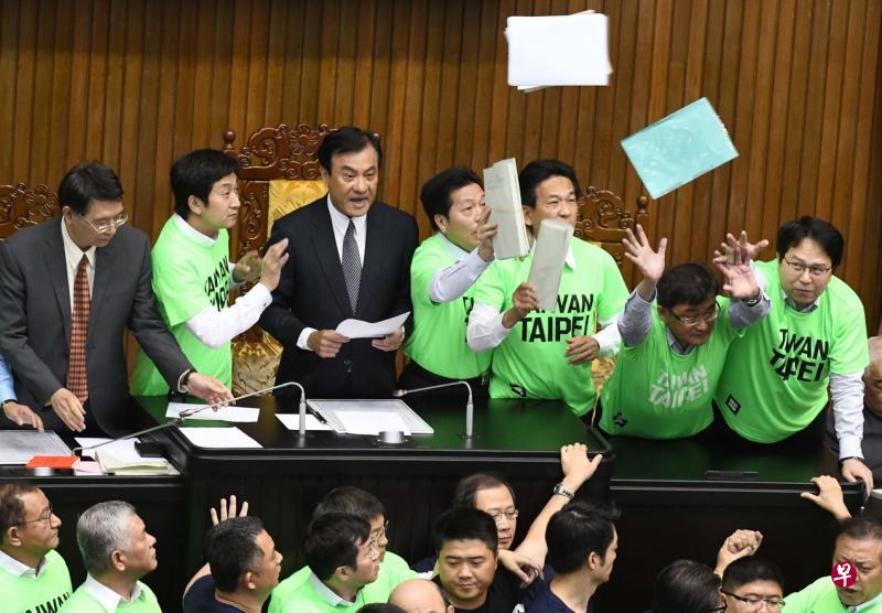 台湾议会中政党恶斗的经典一幕：立法院长苏嘉全（主席台左三）4月20日在主席台下朝野立委混战、台上文件飞舞的状况下，宣读军人年金改革修正草案表决结果。（法新社）