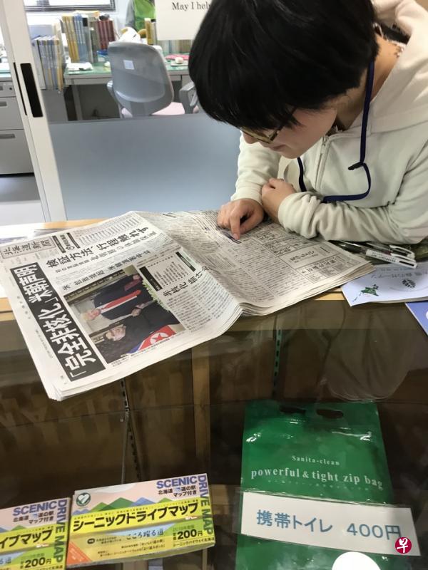 北海道一个询问中心的职员津津有味地读着在新加坡举行的特金会新闻。（读者提供）