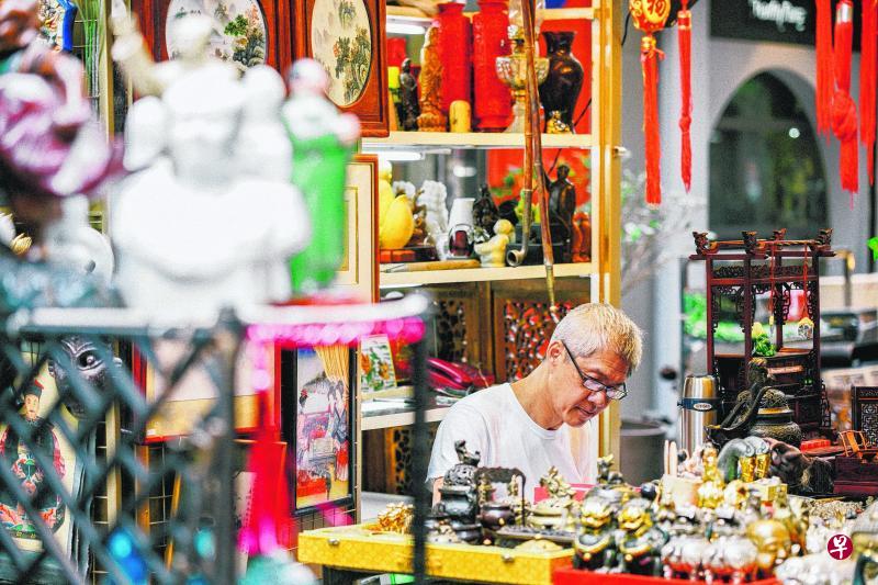 猫街有许多卖中国艺术品的摊位。这摊位售卖许多古色古香的中国饰品和书画，摊主在端详着自己手中的宝物。（邓凯铭/摄）