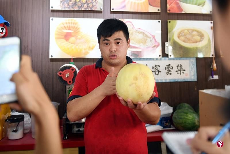 水果店员李先生出示店内售卖的蜜瓜。（蔡振鸿摄）