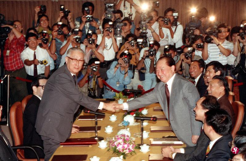 中国海协会会长汪道涵（右）和台湾海基会董事长辜振甫于1993年4月27日在新加坡举行了第一次“汪辜会谈”。当时负责摄影的熊俊华拍下了两位领导人隔着长桌握手的历史照片。（熊俊华摄） 