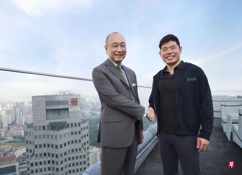 大华银行副主席兼总裁黄一宗（左）和Grab首席执行官陈炳耀握手宣布成立合作伙伴关系。（大华银行提供）