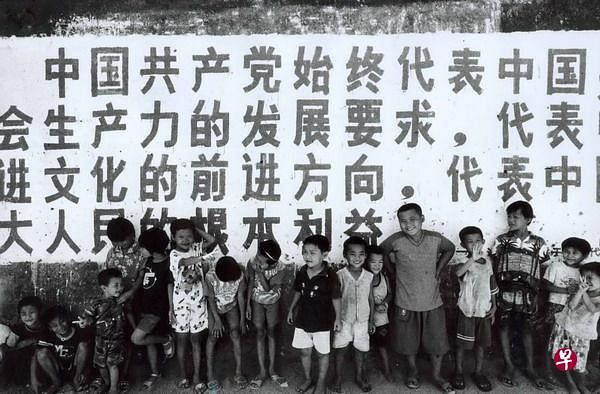 ▲海南岛陵水龙门村的儿童2002年在“三个代表”的标语下合影。（互联网）