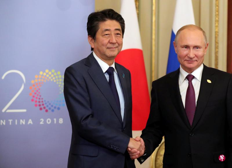 安倍（左）和普京在会谈上握手合照。（路透社）