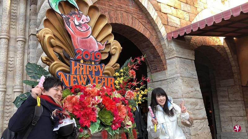 日本游客围着山猪卡通造型拍照，希望2019年大跃进。（符祝慧摄）
