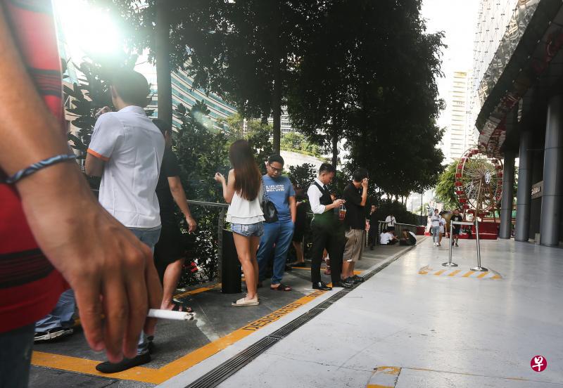 根据记者昨天下午的观察，爱雍·乌节外的一个特定吸烟区内站满烟客，有些烟客因此得站到特定吸烟区黄色格子外吸烟。（梁伟康摄）