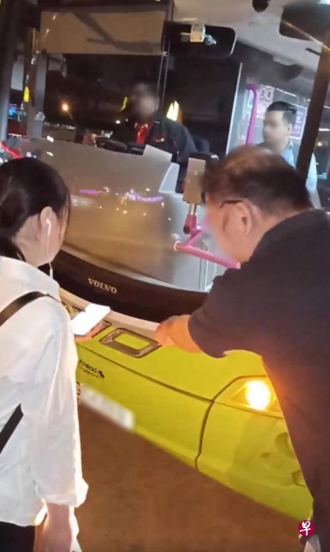 一名女乘客（左）指巴士车长没有提醒她下车，导致她错过目的地，并以身挡车不让巴士离开，遭车上一名男乘客（右）下车指责她说：“你不要耽误全村人跟着你一起迟回家。”（视频截图）