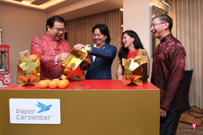 华侨银行执行总裁钱乃骥（左起）向本地创意工匠Paper Carpenter创办人兼创意总监蔡镇宇和营销总监伍碧丽讨教如何组装“吉祥金猪”。在旁是华侨银行环球商业银行部总裁高体良。（华侨银行提供）