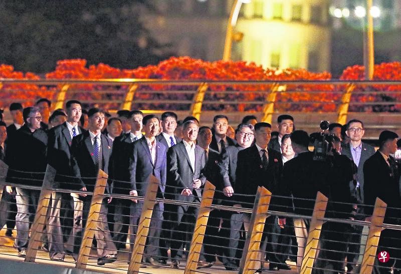 金正恩（中间戴眼镜者）在我国外交部长维文等人的陪同下，夜游我国鱼尾狮公园。（档案照片）